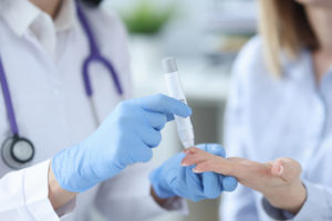 Nurse drawing blood from patient with lancet closeup