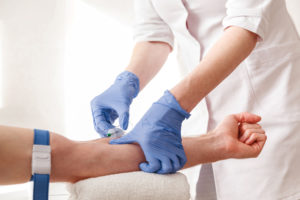 The nurse draws blood from a vein for test.
